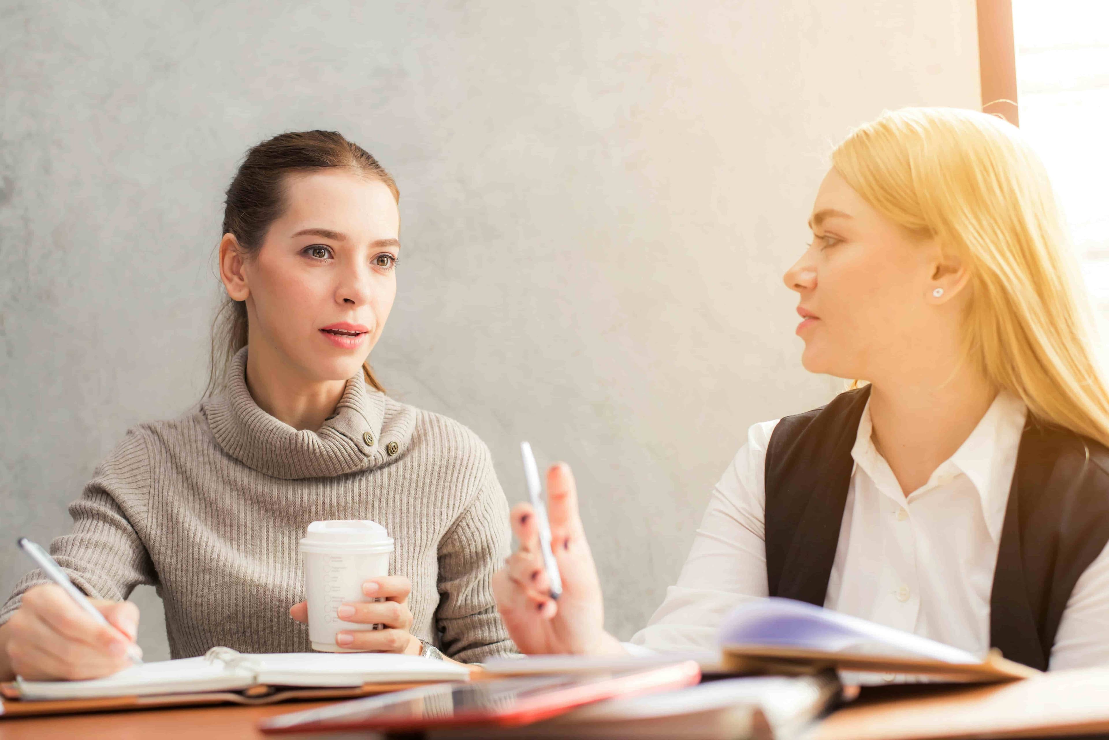 Two people talking to each other, making notes