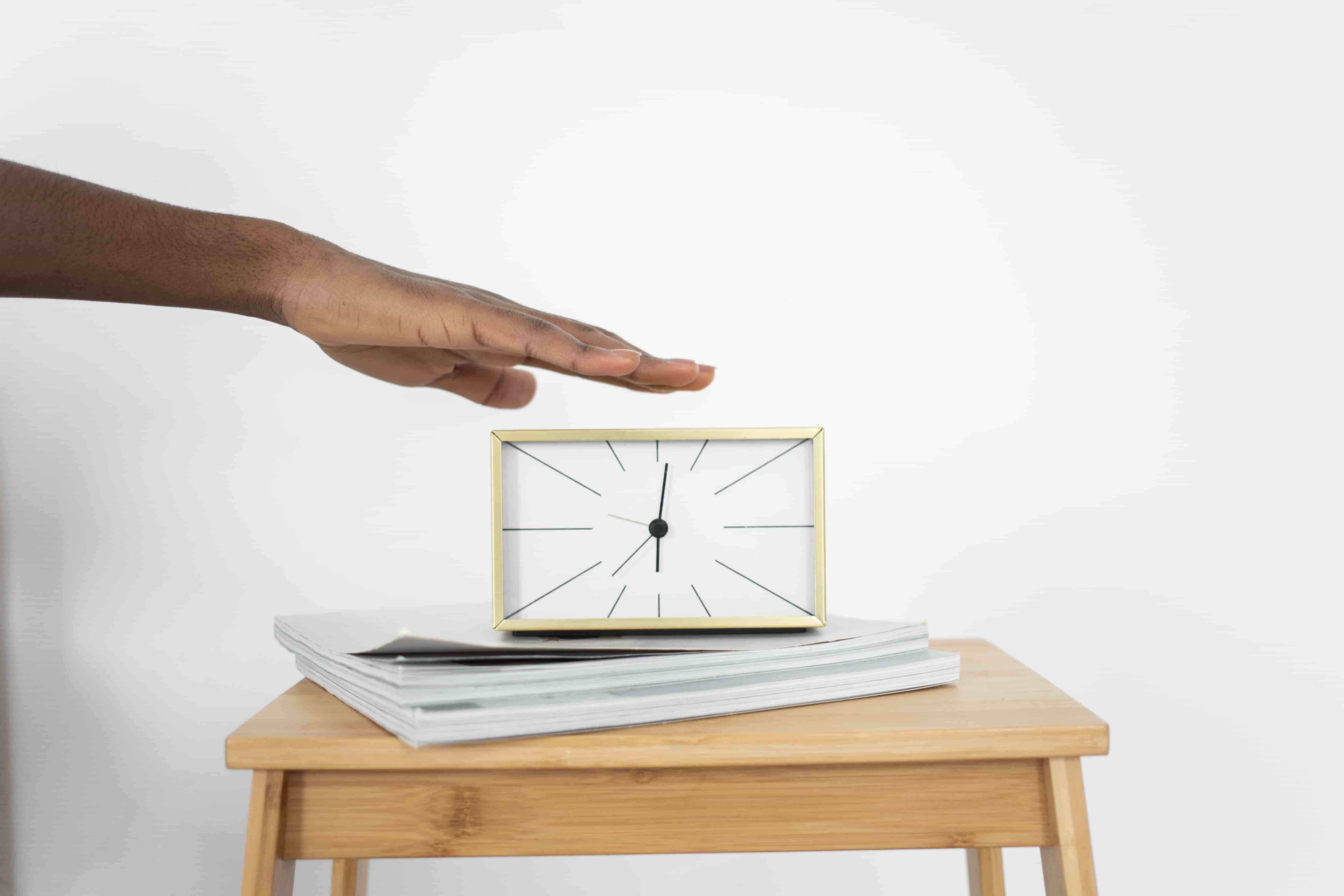 A hand pressing a clock to represent structured time blocks